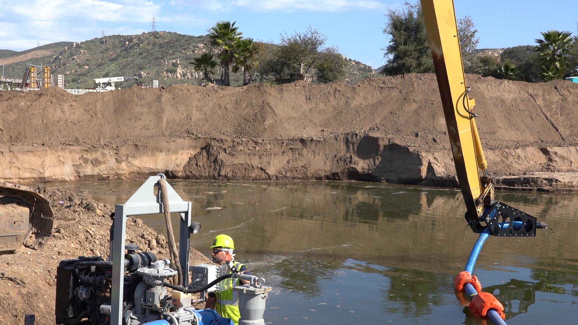 Construction Worker Operating Machinery Near Water Body Construction worker in helmet near water site