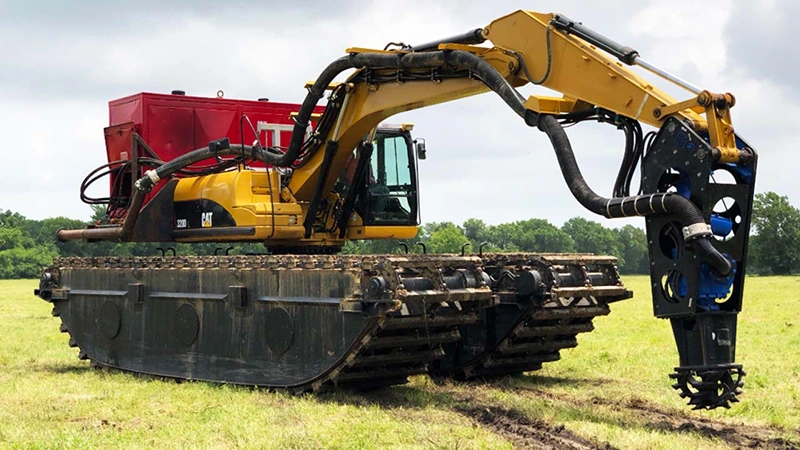Amphibious excavator equipped with sealed pontoon undercarriage and hydraulic power unit, ready for shallow-water dredging and wetland sediment removal operations