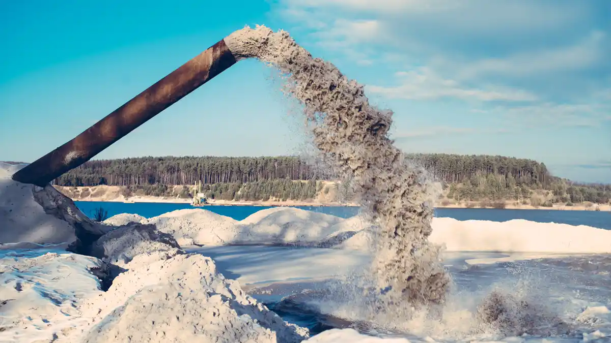 Delivered Sand from a Discharge Pipe Sand slurry pouring from an elevated discharge pipe onto stockpiles beside a lake