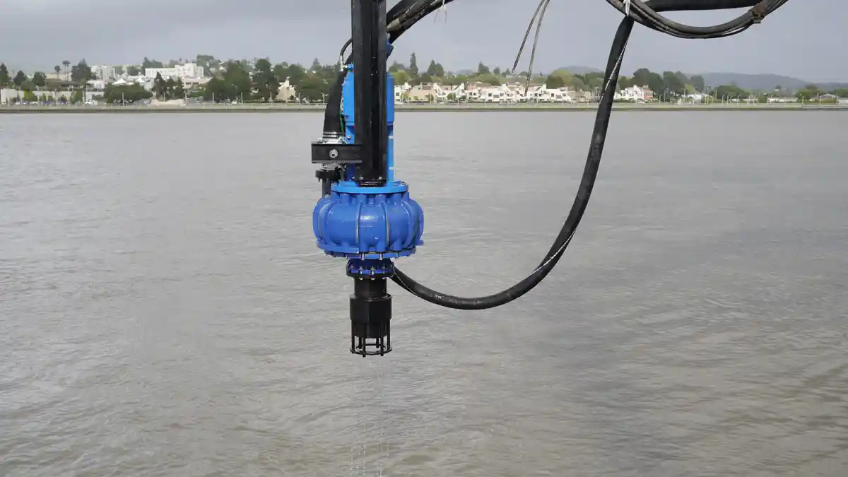 Suspended Dredge Pump over Water Blue EDDY Pump dredge pump suspended above open water on a boom with hydraulic hoses