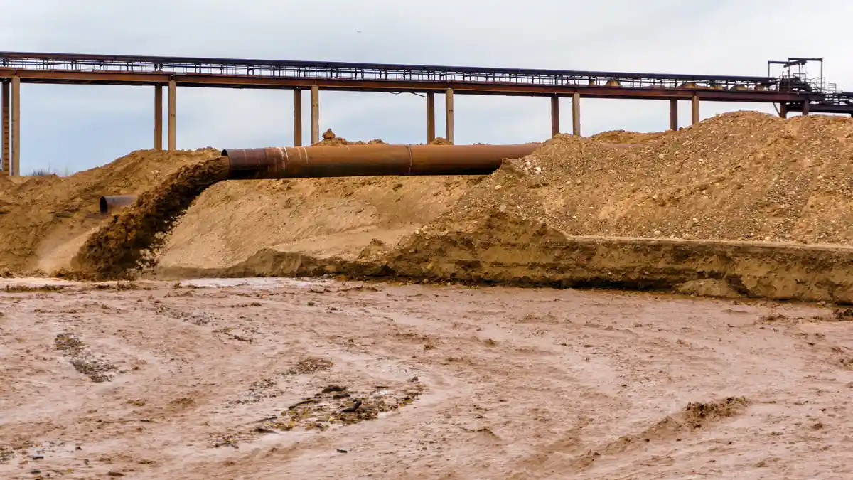 Sand Slurry Pipeline Discharge Rusted slurry pipeline discharging sand onto a fill area beneath an elevated pipe rack